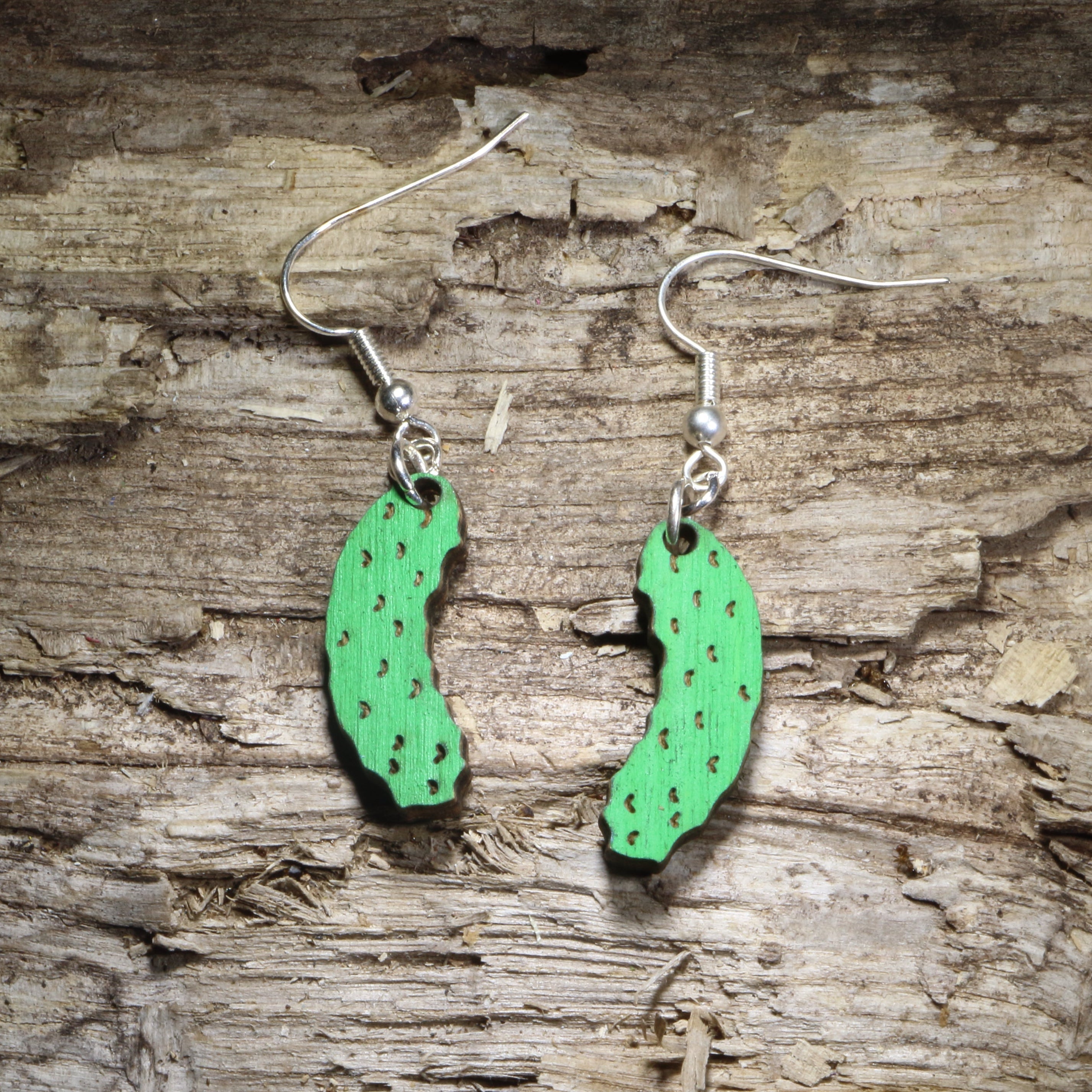 Handcrafted pickle wooden dangle earrings featuring hand-painted bright green dill pickles with realistic texture details. Lightweight wooden food earrings with hypoallergenic .925 sterling silver hooks, perfect for pickle lovers, foodies, deli enthusiasts, pickleball fans, quirky gifts, farmers market outings, and fun everyday accessories.