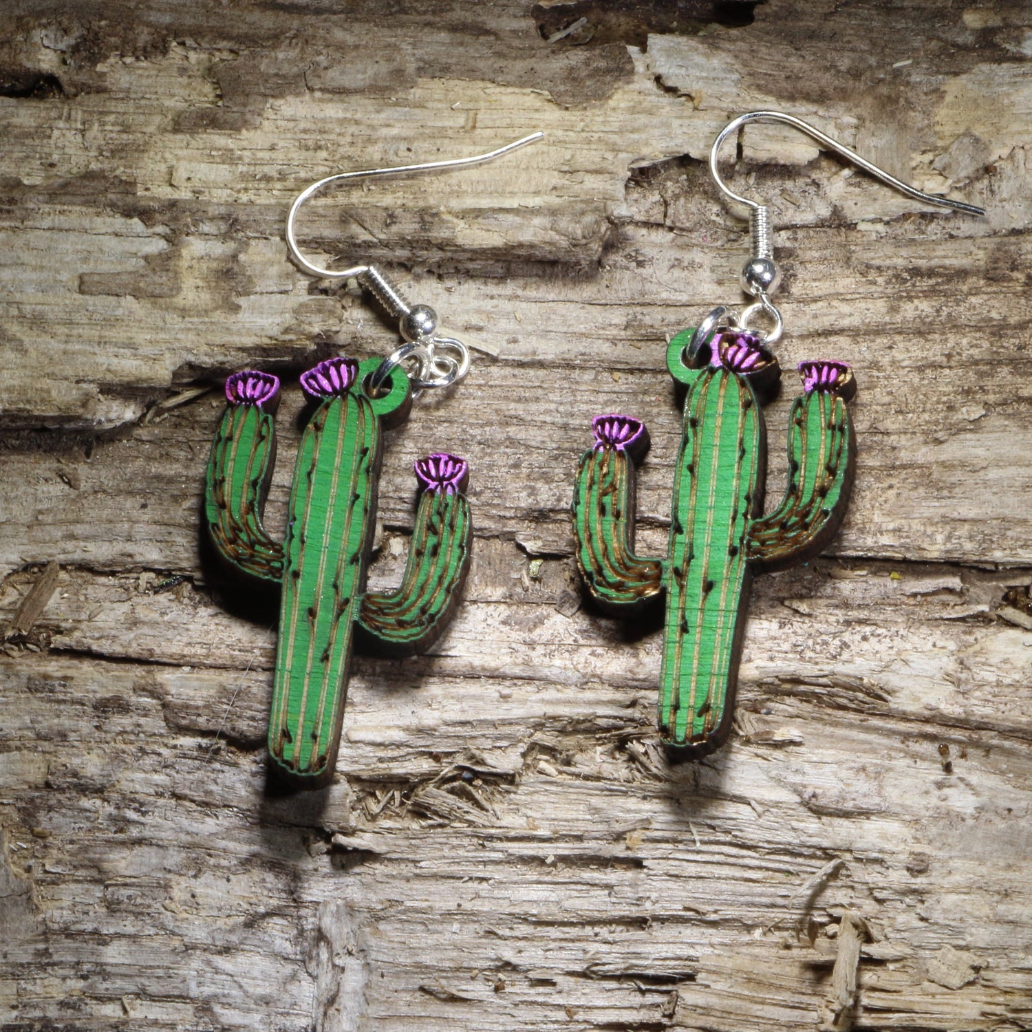 Handcrafted saguaro cactus wooden dangle earrings featuring a hand-painted green desert cactus with blooming purple flowers. Lightweight laser-cut wooden earrings with hypoallergenic .925 sterling silver hooks, perfect for Southwest style, Arizona lovers, desert enthusiasts, cactus collectors, succulent fans, and handmade botanical jewelry.