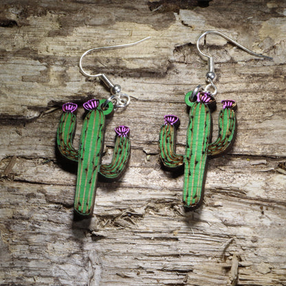 Handcrafted saguaro cactus wooden dangle earrings featuring a hand-painted green desert cactus with blooming purple flowers. Lightweight laser-cut wooden earrings with hypoallergenic .925 sterling silver hooks, perfect for Southwest style, Arizona lovers, desert enthusiasts, cactus collectors, succulent fans, and handmade botanical jewelry.