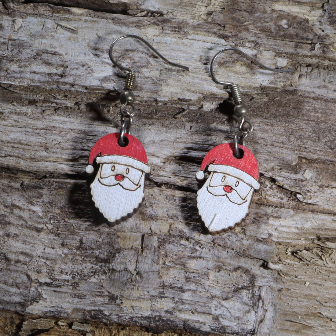 Handcrafted wooden Santa Claus dangle earrings featuring a cheerful Santa face with a bright red hat and classic white beard. These lightweight Christmas earrings are hand-painted and finished with hypoallergenic .925 sterling silver hooks, making them a festive accessory for holiday parties, Christmas markets, family gatherings, Secret Santa gifts, and the entire winter season.