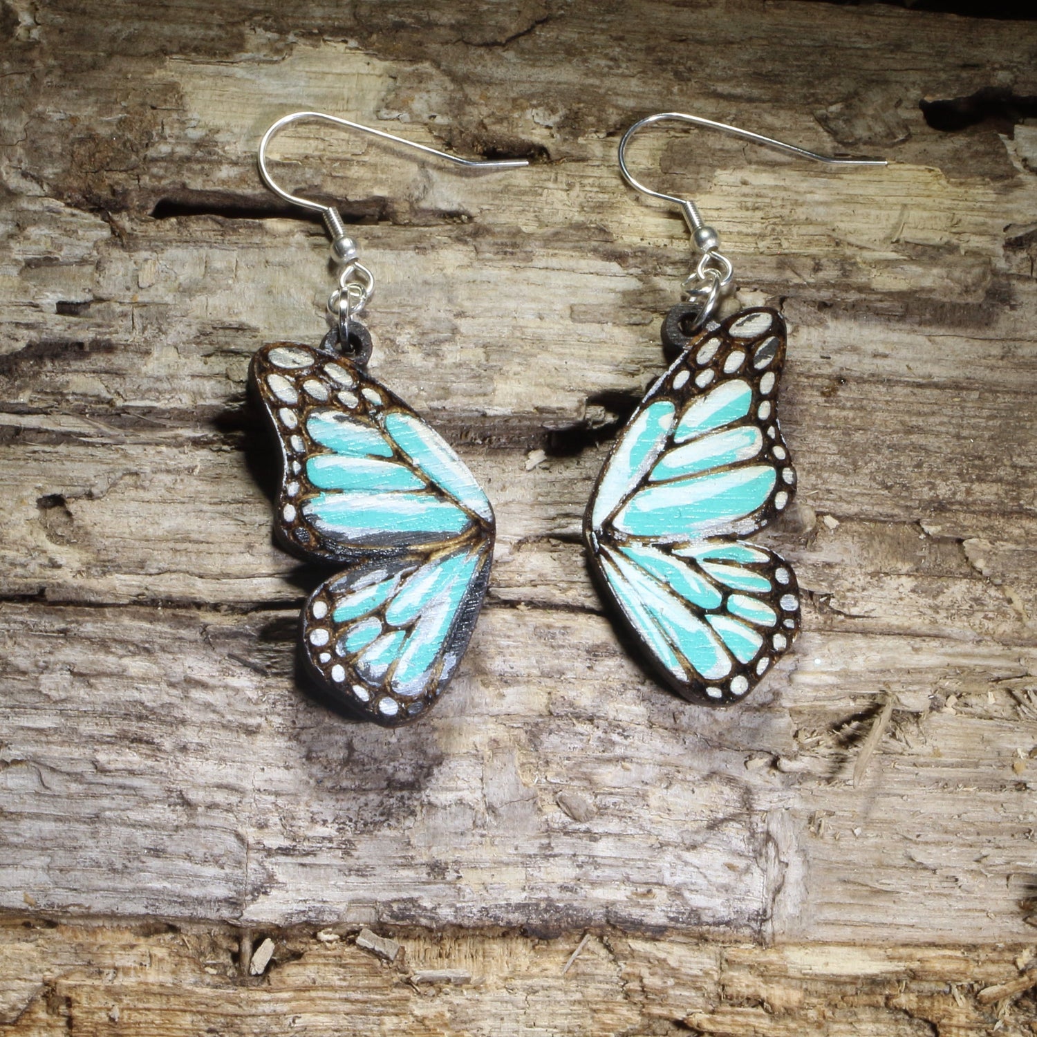 Handmade blue butterfly wing wooden dangle earrings featuring vibrant blue butterfly wings with detailed engraved accents. Lightweight nature-inspired earrings crafted from wood with hypoallergenic .925 sterling silver hooks, perfect for butterfly lovers, gardeners, nature enthusiasts, insect fans, and unique woodland jewelry collectors.