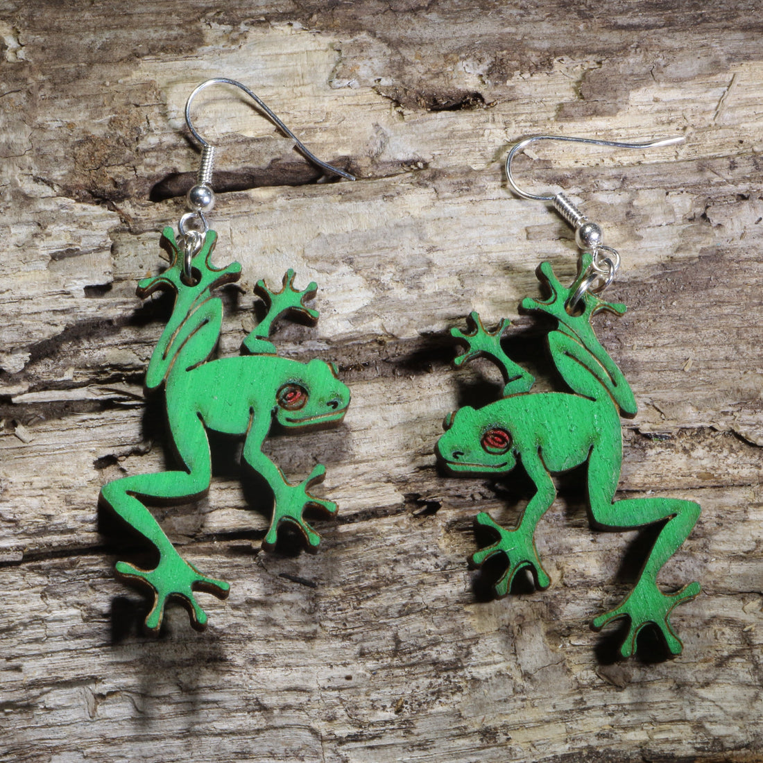Handmade green tree frog wooden dangle earrings featuring detailed laser-cut frogs with bright green painted finish and red eyes. Lightweight frog earrings crafted from wood with hypoallergenic .925 sterling silver hooks, perfect for amphibian lovers, nature enthusiasts, wildlife fans, rainforest lovers, and unique animal jewelry collectors.