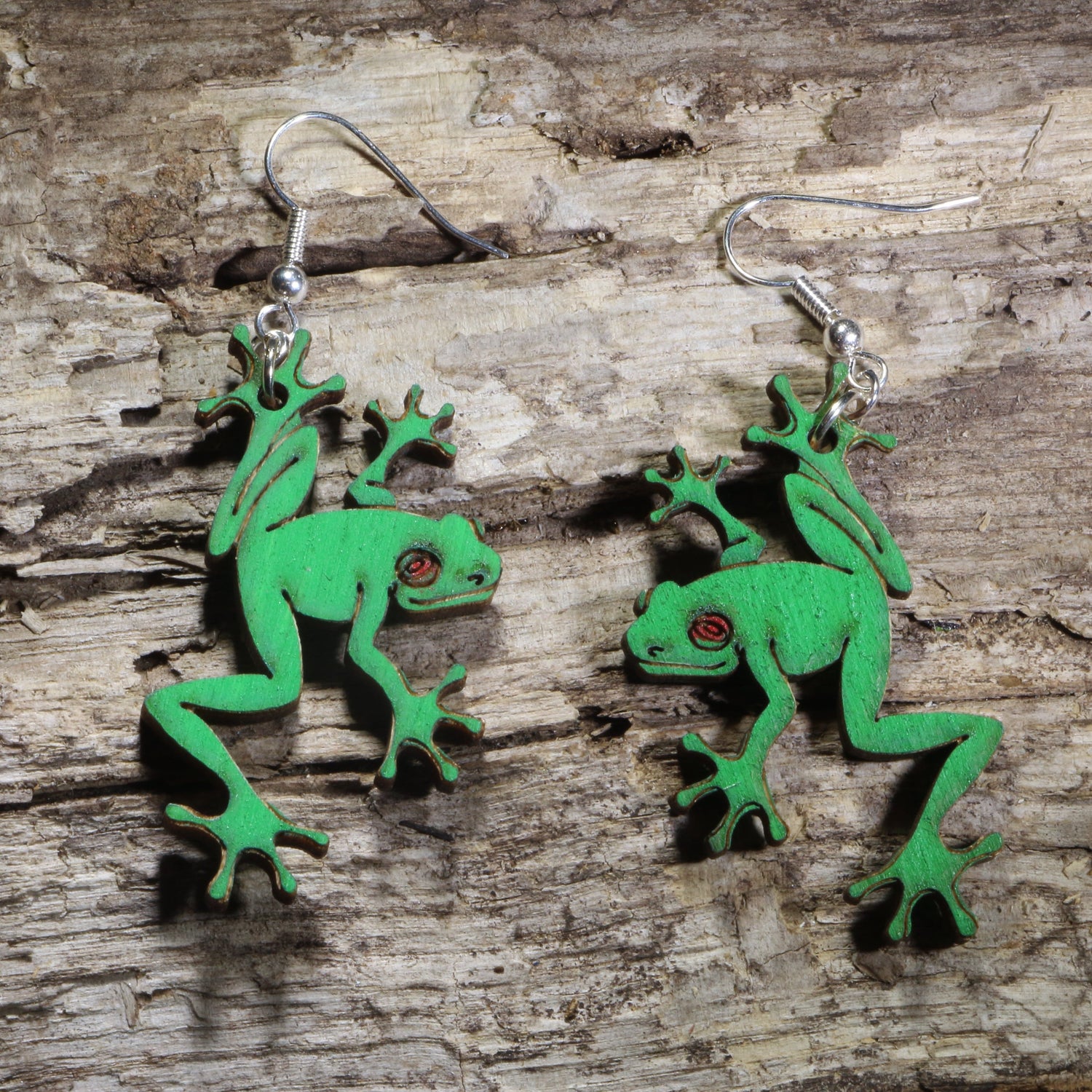 Handmade green tree frog wooden dangle earrings featuring detailed laser-cut frogs with bright green painted finish and red eyes. Lightweight frog earrings crafted from wood with hypoallergenic .925 sterling silver hooks, perfect for amphibian lovers, nature enthusiasts, wildlife fans, rainforest lovers, and unique animal jewelry collectors.