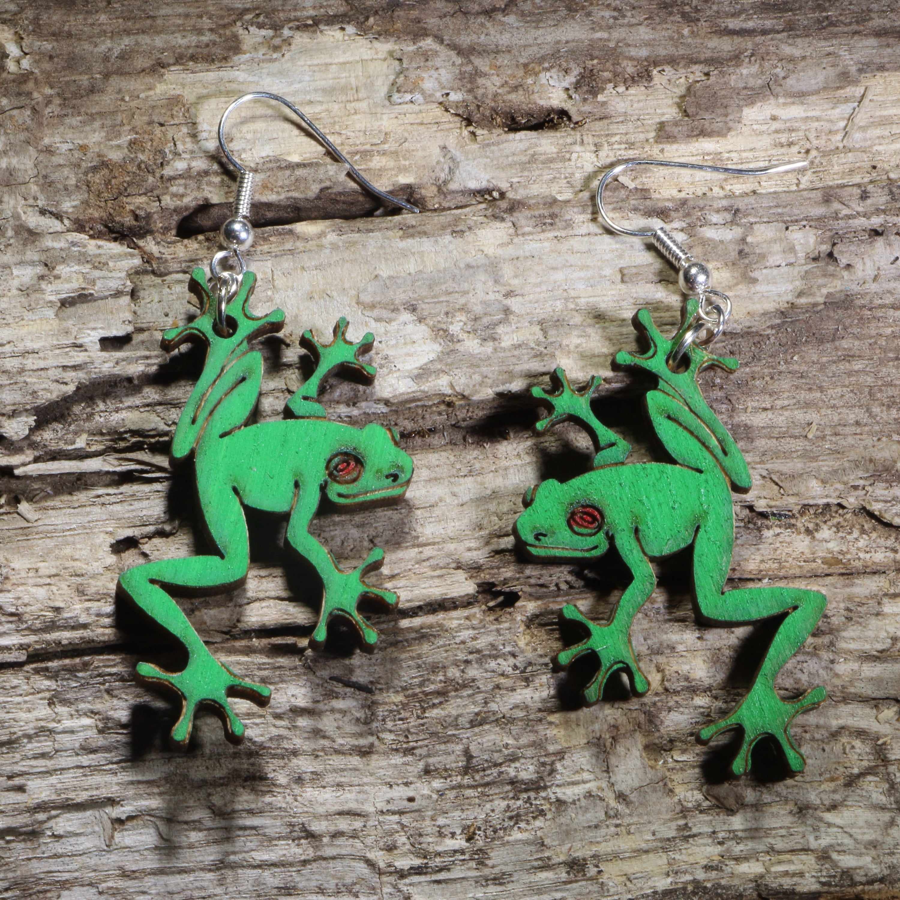 Handmade green tree frog wooden dangle earrings featuring detailed laser-cut frogs with bright green painted finish and red eyes. Lightweight frog earrings crafted from wood with hypoallergenic .925 sterling silver hooks, perfect for amphibian lovers, nature enthusiasts, wildlife fans, rainforest lovers, and unique animal jewelry collectors.