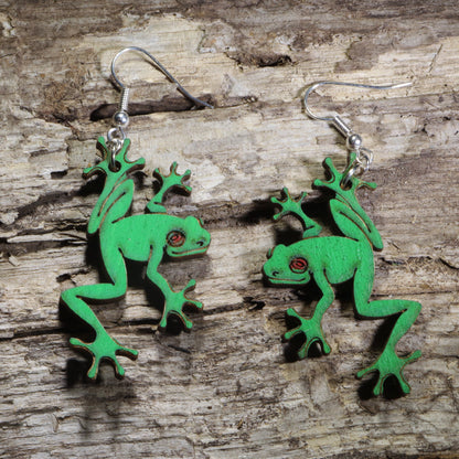 Handmade green tree frog wooden dangle earrings featuring detailed laser-cut frogs with bright green painted finish and red eyes. Lightweight frog earrings crafted from wood with hypoallergenic .925 sterling silver hooks, perfect for amphibian lovers, nature enthusiasts, wildlife fans, rainforest lovers, and unique animal jewelry collectors.