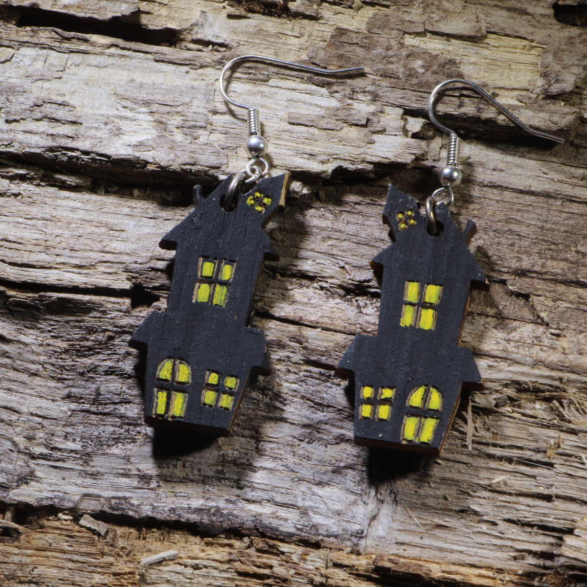 Hand-painted wooden haunted house dangle earrings featuring a spooky black house with glowing yellow windows. Lightweight Halloween earrings with hypoallergenic .925 sterling silver hooks, perfect for haunted house fans, spooky season, Halloween parties, ghost tours, and anyone who loves eerie Halloween jewelry.