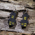 Hand-painted wooden haunted house dangle earrings featuring a spooky black house with glowing yellow windows. Lightweight Halloween earrings with hypoallergenic .925 sterling silver hooks, perfect for haunted house fans, spooky season, Halloween parties, ghost tours, and anyone who loves eerie Halloween jewelry.