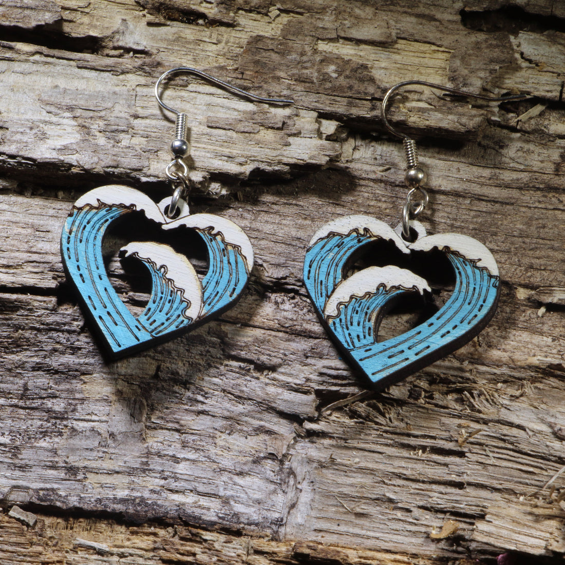 Hand-painted wooden heart wave dangle earrings featuring an ocean wave flowing through an open heart design. Lightweight beach-inspired earrings with hypoallergenic .925 sterling silver hooks, perfect for surfers, ocean lovers, beach enthusiasts, coastal style, sea lovers, and anyone who carries the beach in their heart.