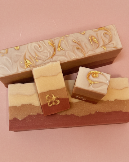 Three layered soap bars with decorative designs on a pink background