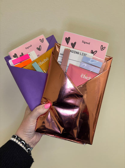 Hand holding a metallic rose gold holder with colorful cards against a plain background