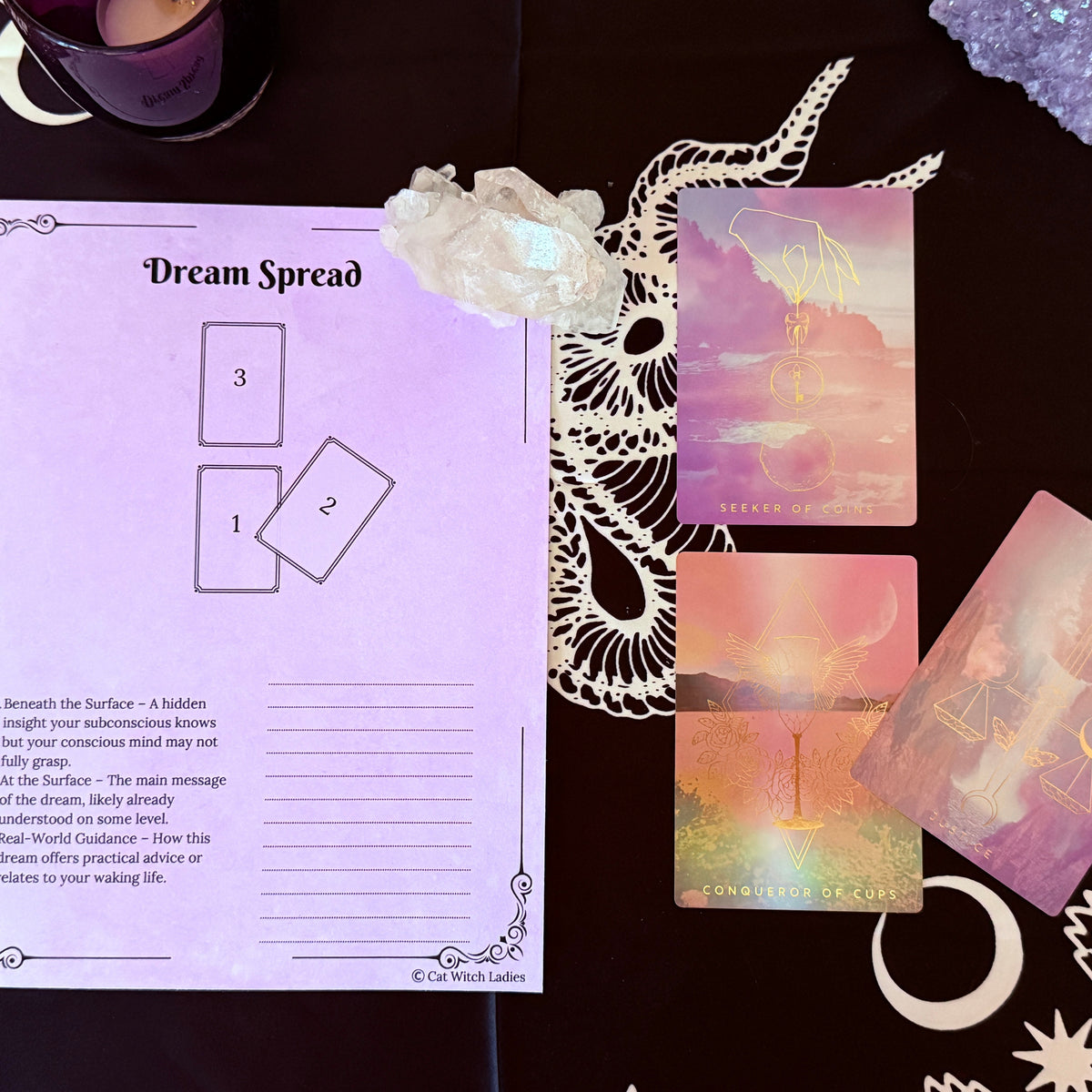 A tarot card reading kit laid out on a dark patterned cloth, featuring a printed &