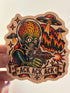 A hand holds a die-cut sticker featuring a retro-style alien-themed illustration with a green skull-headed figure in space gear firing a cannon, surrounded by UFOs, stars, and the text &