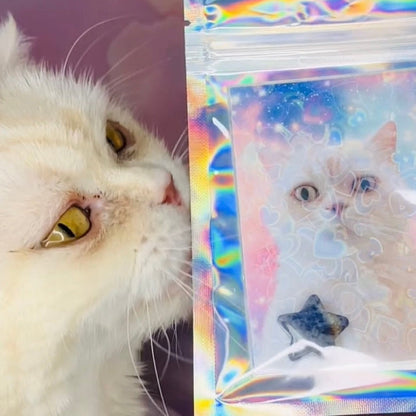 A white cat with yellow eyes looks at a small holographic pouch held by a hand. The pouch contains a printed photo of a white cat with a star charm inside.
