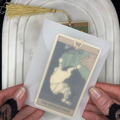 A person holds a tarot card deck in a translucent sleeve, showing the &