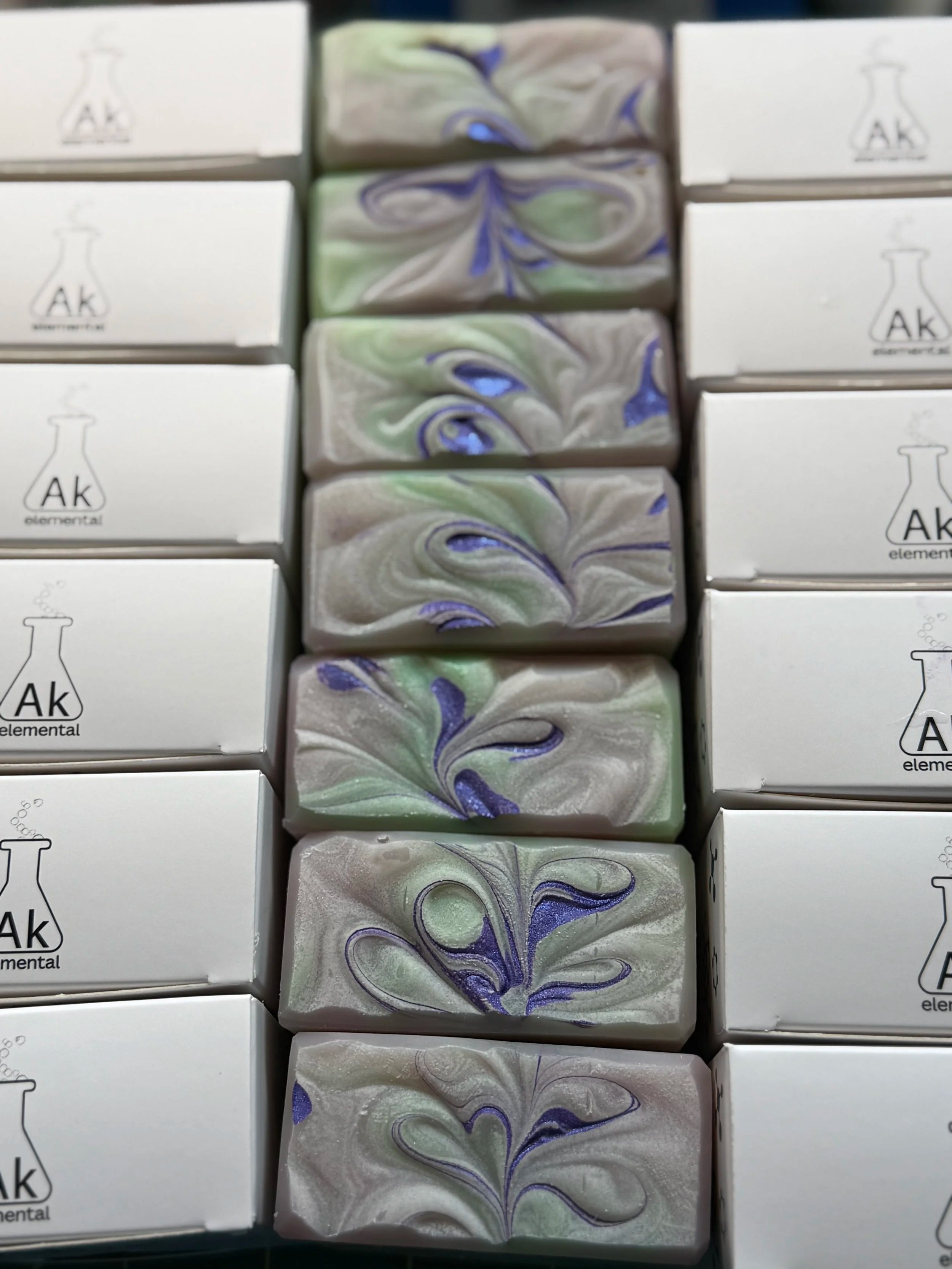 Tops of soap boxes and tops of soaps with decorative purple swirls.