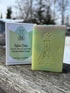 Handcrafted pale green Spa Day soap with AK Elemental logo, packaged beside it on a rustic table with a snowy Alaska backdrop.