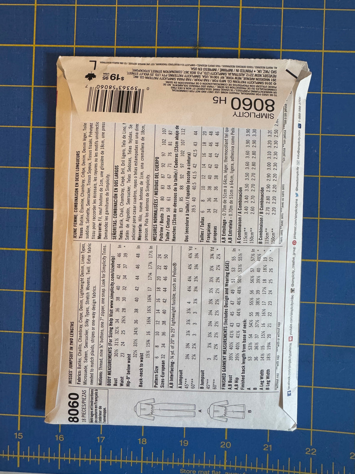A sewing pattern envelope for Simplicity 8060 H5 is shown flat on a blue cutting mat with yellow grid lines.