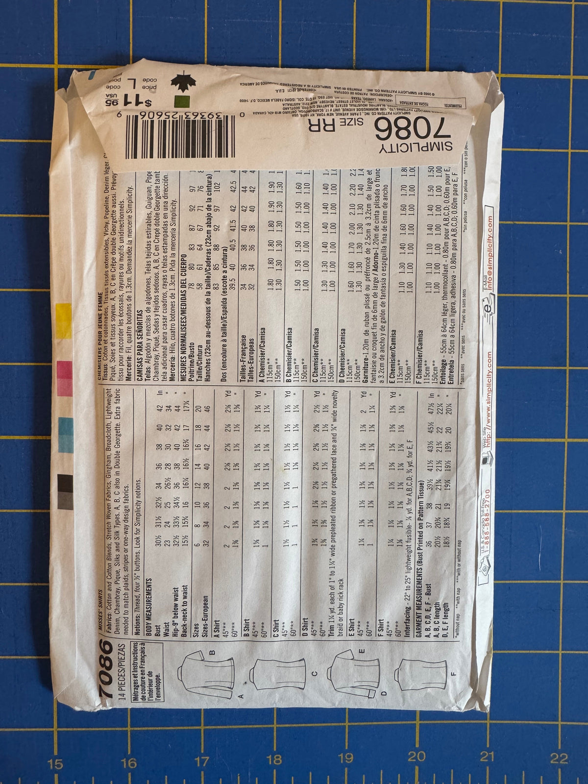 A flat lay of a Sew-It! brand sewing pattern envelope, pattern number 1086, showing the back with size charts and garment illustrations, placed on a blue cutting mat.