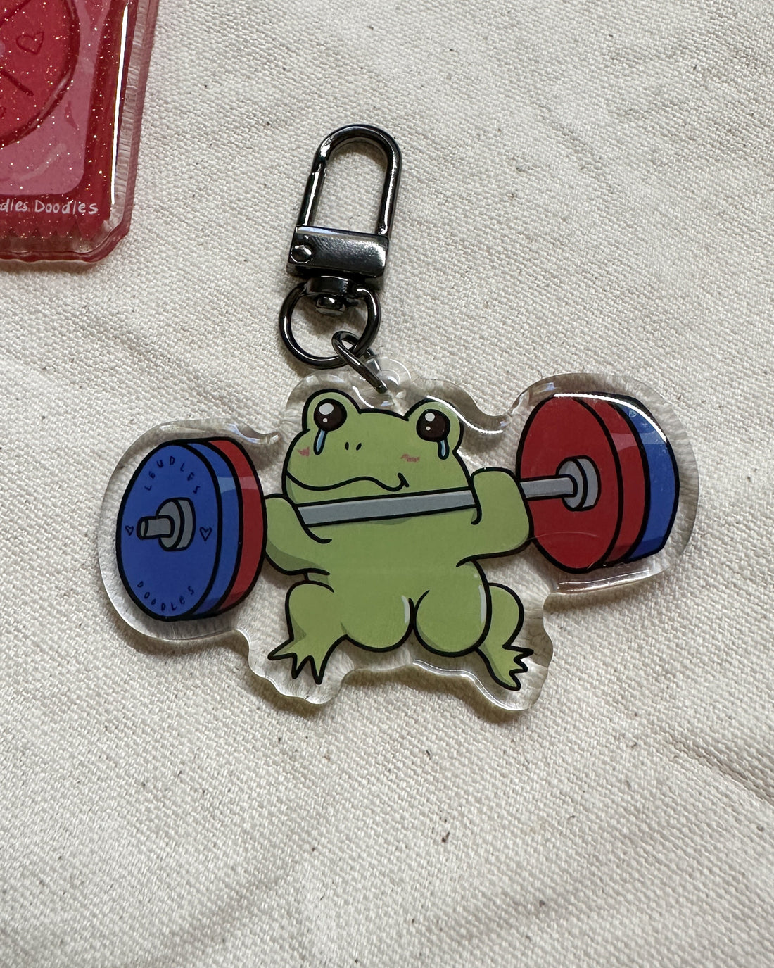 Keychain with a frog lifting weights