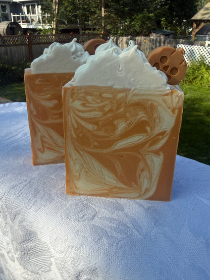 Two Square soap bar with swirls of cream, orange, and warm brown, sitting on a white cloth.