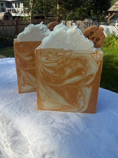 Two Square soap bar with swirls of cream, orange, and warm brown, sitting on a white cloth.