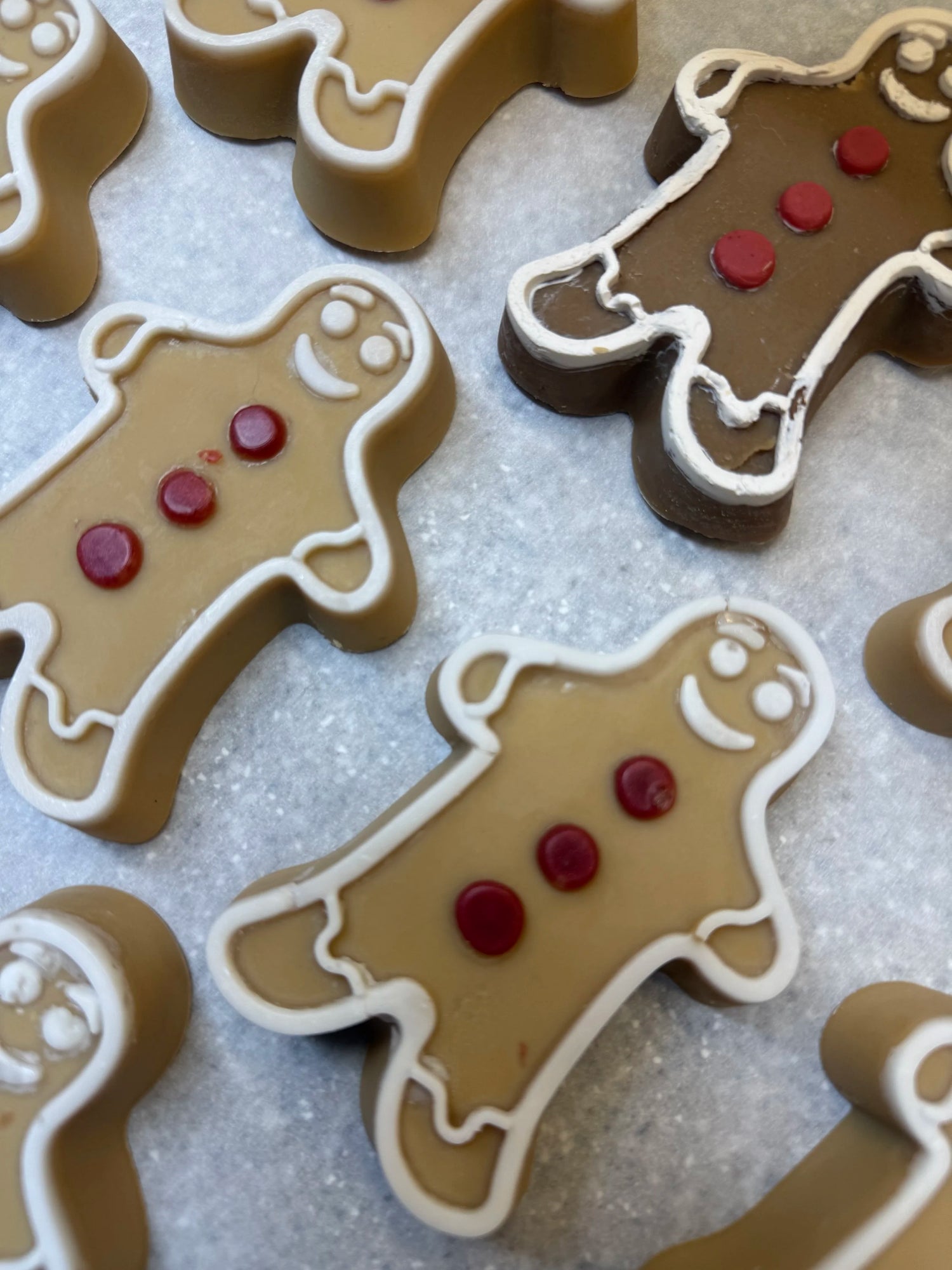 Gingerbread Man soap with a golden-brown body, white icing details, and three red buttons on parchment paper.