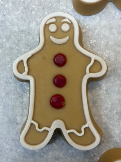 Gingerbread Man soap with a golden-brown body, white icing details, and three red buttons on parchment paper.