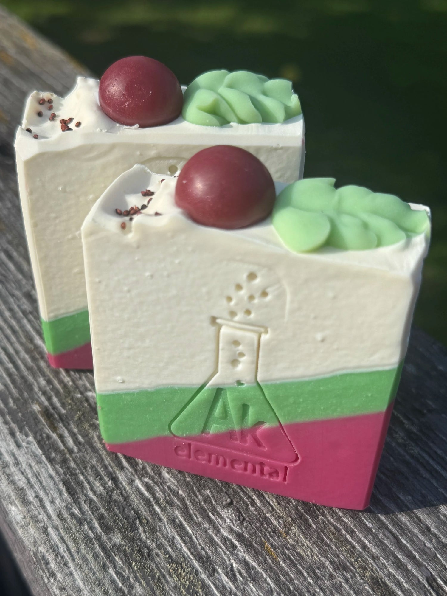 Handcrafted Wild Cranberry soap bar with cream, evergreen green and cranberry red diagonal layers and festive round soap embeds on top.