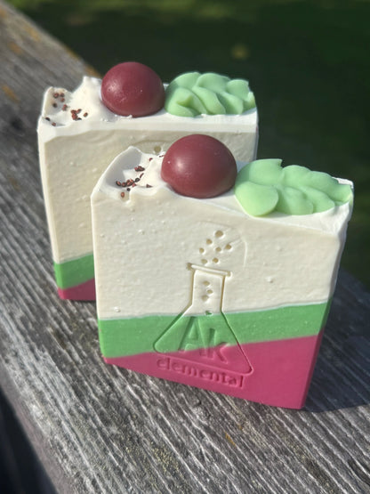 Handcrafted Wild Cranberry soap bar with cream, evergreen green and cranberry red diagonal layers and festive round soap embeds on top.