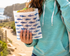 Person holding a sandwich wrapped in a paper bag with shark pattern outdoors