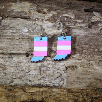 Hand-painted wooden Indiana transgender pride dangle earrings featuring the Indiana state silhouette with pink, blue, and white transgender pride stripes, hypoallergenic sterling silver hooks, and lightweight LGBTQ+ state pride jewelry by Cate&