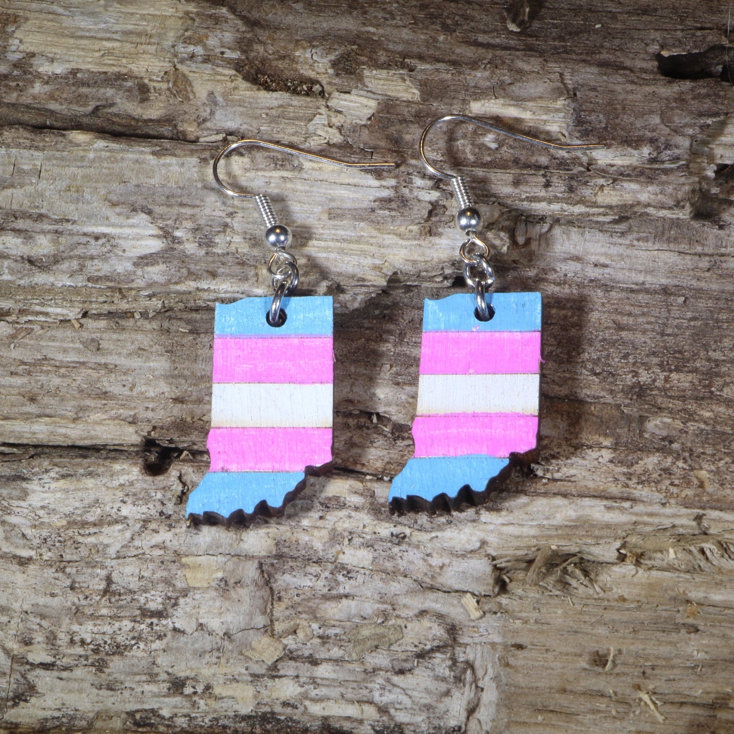 Hand-painted wooden Indiana transgender pride dangle earrings featuring the Indiana state silhouette with pink, blue, and white transgender pride stripes, hypoallergenic sterling silver hooks, and lightweight LGBTQ+ state pride jewelry by Cate&