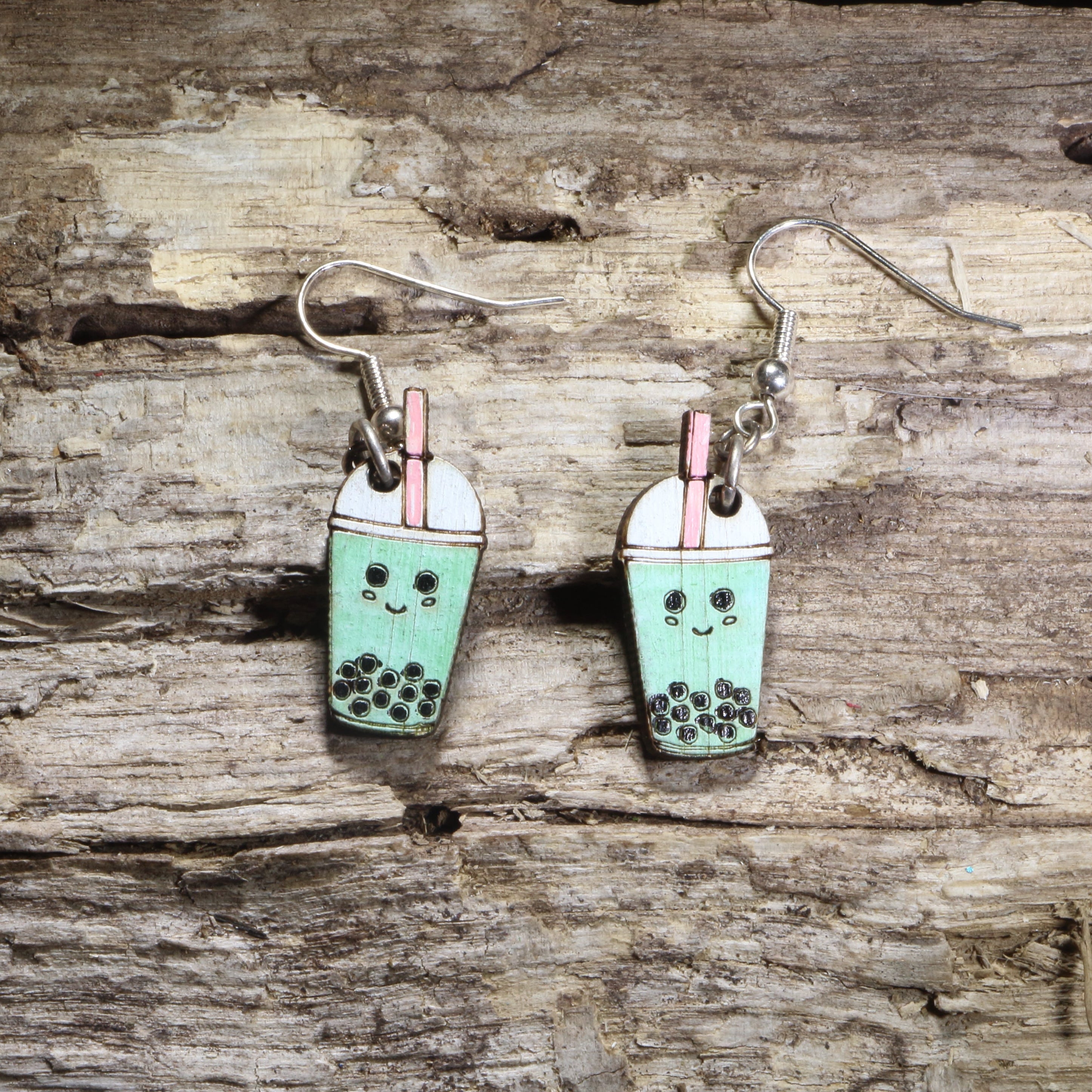 Handcrafted kawaii bubble tea wooden dangle earrings featuring a smiling cup of boba tea with tapioca pearls and a colorful straw. Lightweight laser-cut wooden earrings with hypoallergenic .925 sterling silver hooks, perfect for bubble tea lovers, boba fans, kawaii fashion enthusiasts, food jewelry collectors, and cute everyday accessories.