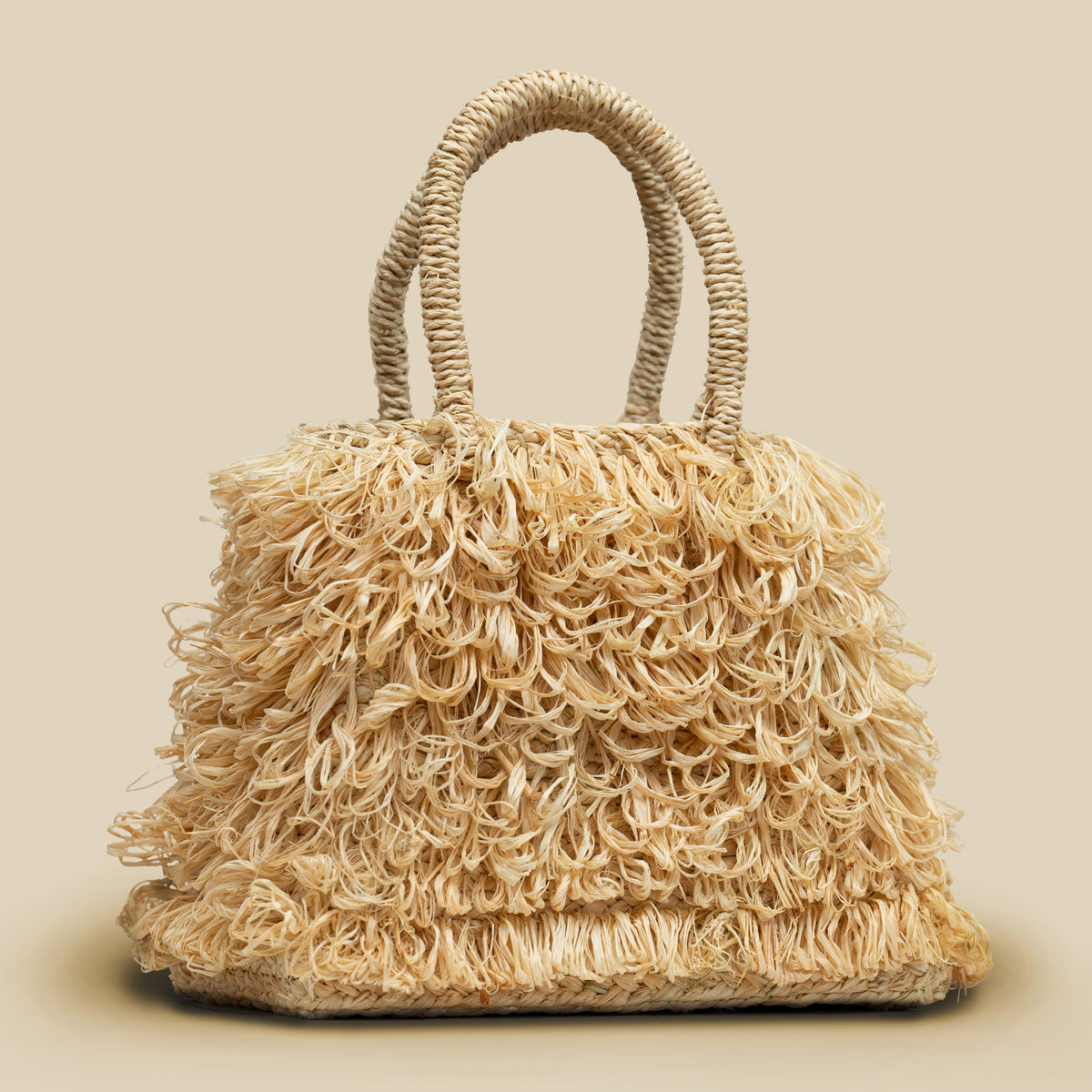 Fair trade Beige raffia hand woven trapezoid mini handbag with looped fringe on a beige background