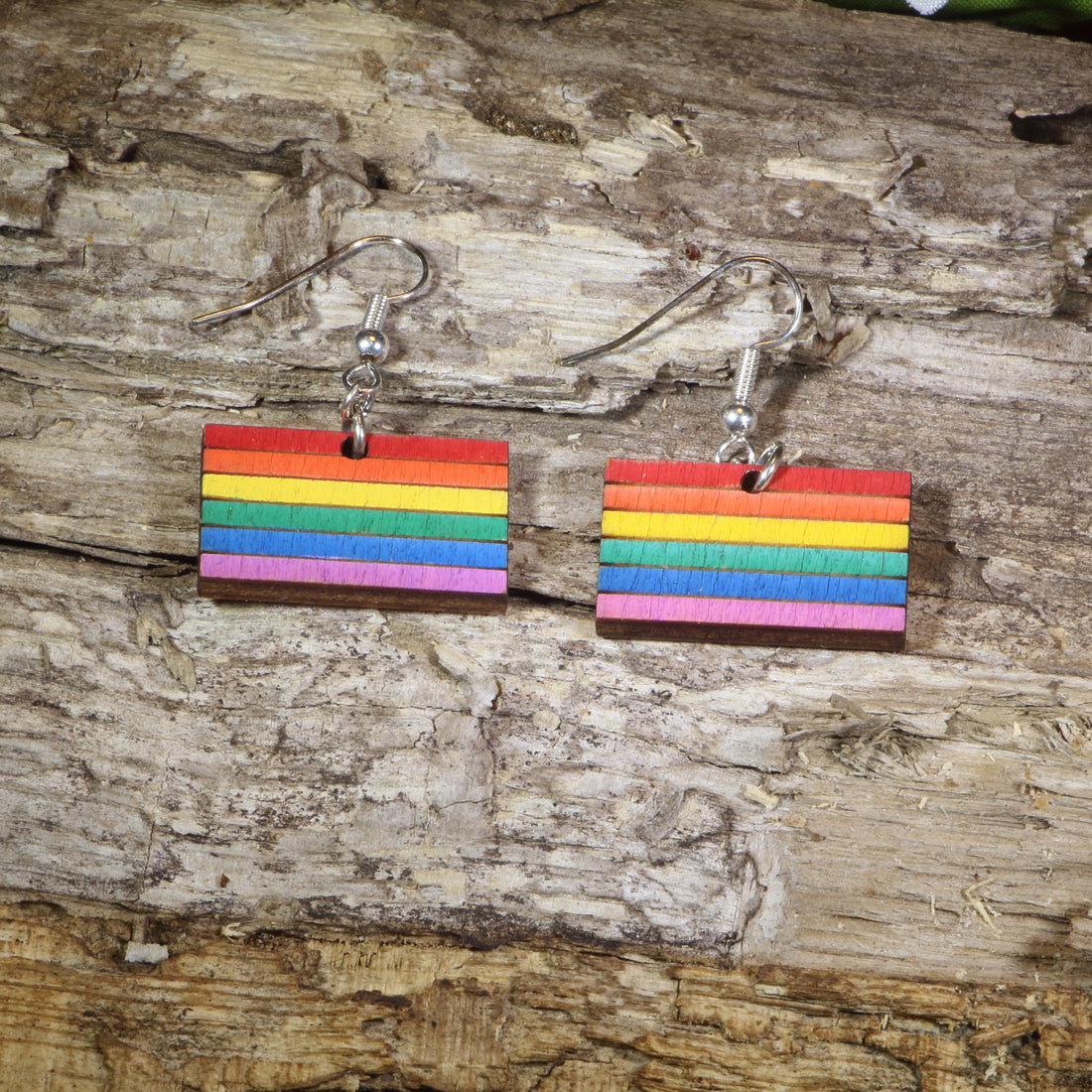 Hand-painted wooden LGBTQ Pride Flag dangle earrings featuring vibrant rainbow flag stripes, hypoallergenic sterling silver hooks, and lightweight LGBTQ+ pride jewelry for advocates, allies, and members of the queer community by Cate&