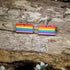 Hand-painted wooden LGBTQ Pride Flag dangle earrings featuring vibrant rainbow flag stripes, hypoallergenic sterling silver hooks, and lightweight LGBTQ+ pride jewelry for advocates, allies, and members of the queer community by Cate&