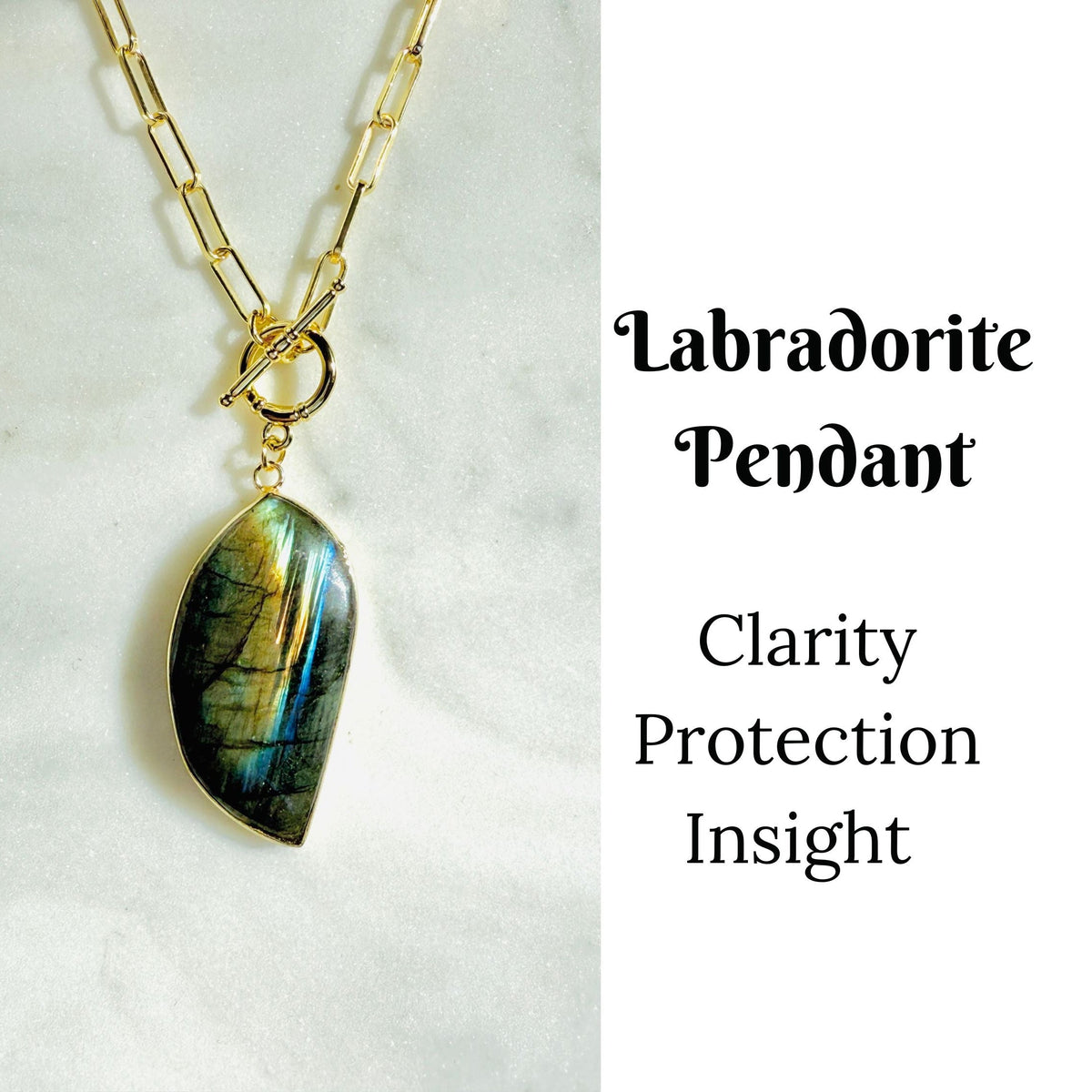 A gold chain necklace with a teardrop-shaped labradorite pendant, displayed on a white marble surface next to text that reads &
