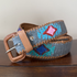 Decorative belt with floral pattern and brown leather buckle on a wooden surface