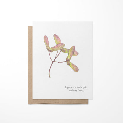 A greeting card with a watercolor painting of maple seeds and a quote by Virginia Wolf on the back. The card is blank inside and comes with a brown kraft envelope.