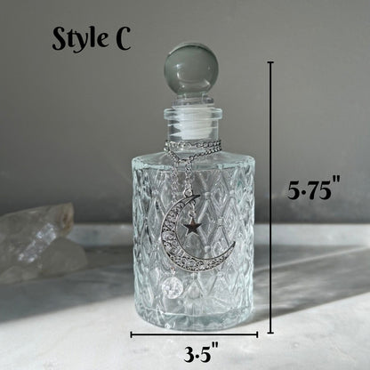 A clear glass decanter with a textured diamond pattern, a silver crescent moon and star design on the front, and a round glass stopper. The image includes dimension lines indicating a height of 5.