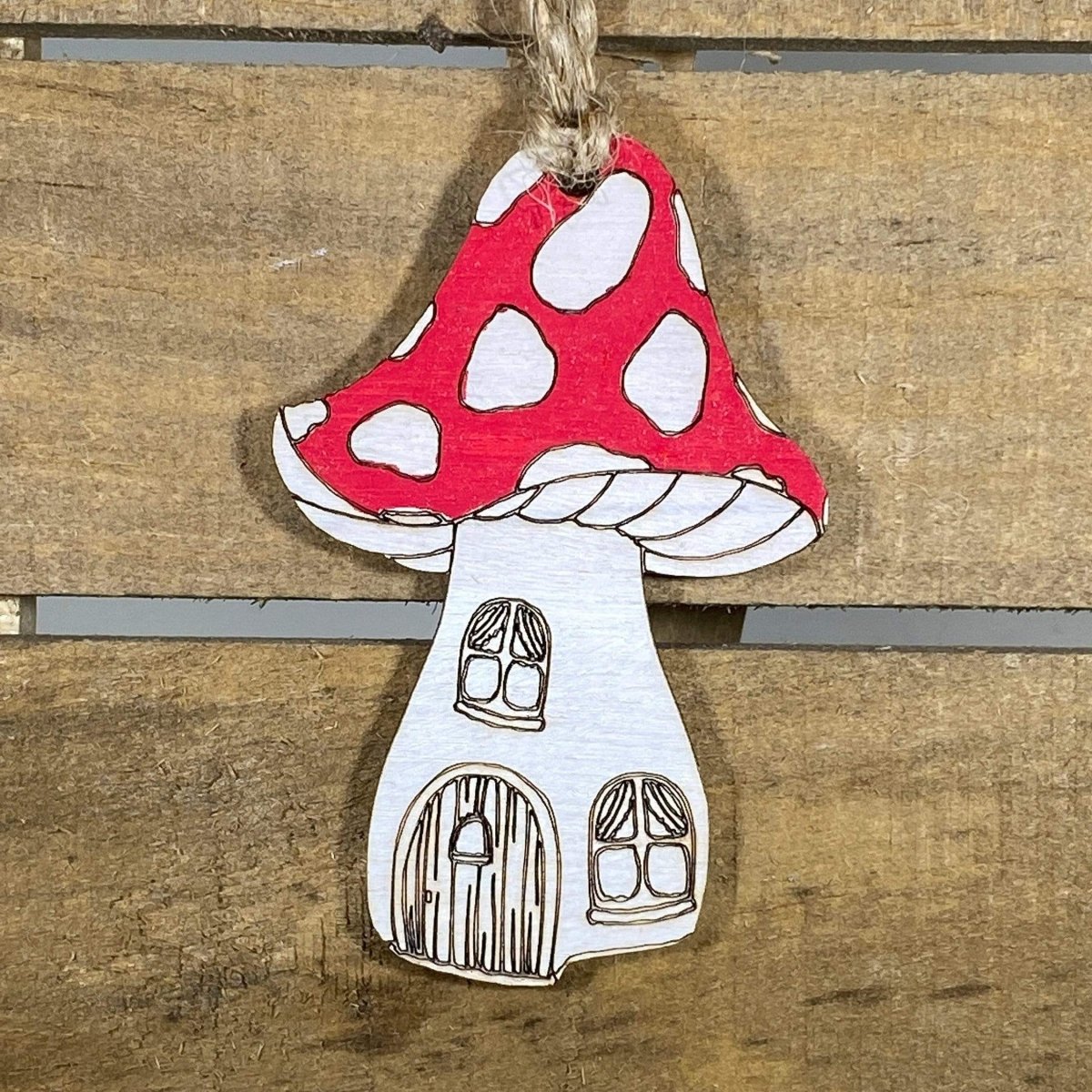 Hand-painted wooden mushroom house Christmas ornament featuring a whimsical toadstool cottage design with charming fairy tale details, festive holiday decor for fantasy lovers and cottagecore enthusiasts by Cate’s Concepts