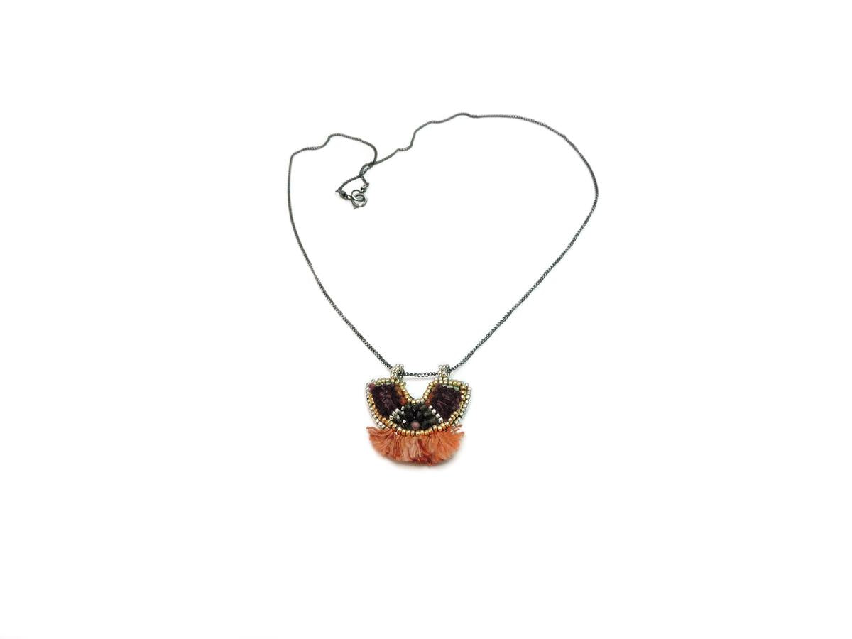 A silver chain with a u-shaped pendant featuring dark red and blue silk, silver and gold beads on ethical leather and coral silk fringe at the bottom, ethical and fair trade jewelry chicago 