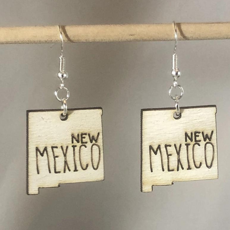 Hand-painted wooden New Mexico state dangle earrings featuring a state-shaped design with bold Southwest-inspired detailing and hypoallergenic sterling silver hooks, lightweight jewelry for New Mexico locals and desert style enthusiasts by Cate’s Concepts

