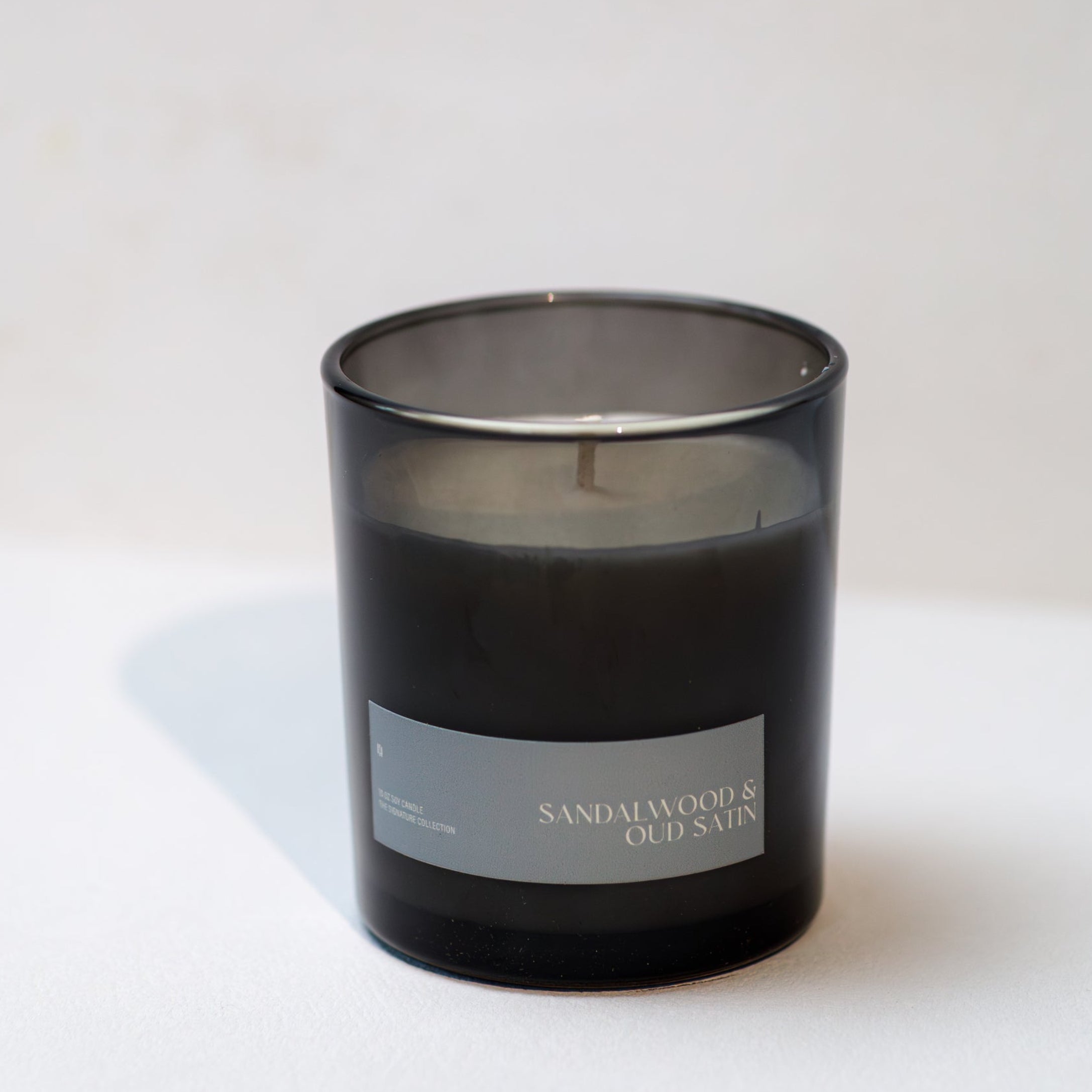 Black candle with a label on a white surface and background