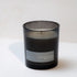 Black candle with a label on a white surface and background