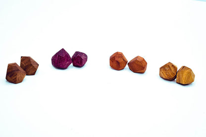 Set of six pairs of hand-finished faceted wood stud earrings, sterling posts, geometric shapes, vibrant colors on white background.