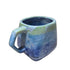 Blue ceramic mug with a greenish handle on a white surface