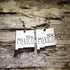 Pair of white New Mexico state-shaped wooden dangle earrings with New Mexico text displayed on rustic weathered wood