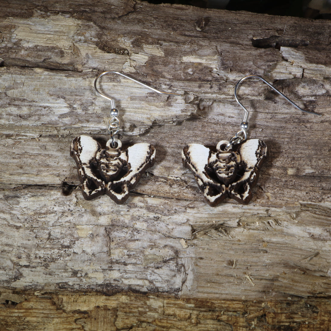 Hand-painted wooden pelvis anatomy dangle earrings featuring an anatomical pelvis design with lightweight construction and hypoallergenic .925 sterling silver hooks, perfect for doctors, nurses, physical therapists, chiropractors, medical students, and healthcare professionals.