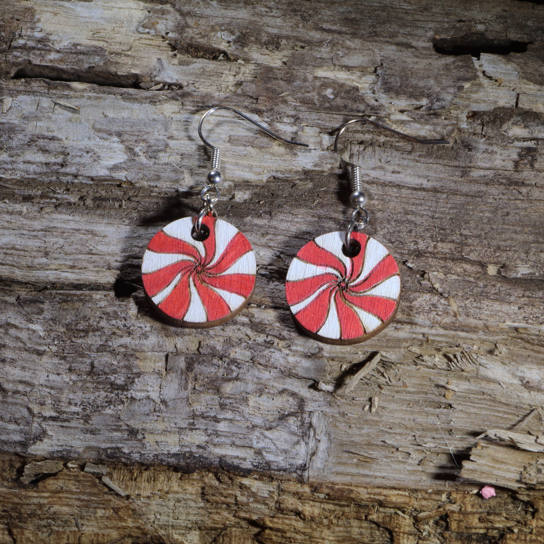 Hand-painted wooden peppermint candy dangle earrings featuring classic red and white swirled peppermint mints. Crafted from lightweight wood with hypoallergenic .925 sterling silver hooks, these festive holiday earrings are perfect for Christmas celebrations, winter parties, candy lovers, cookie exchanges, stocking stuffers, peppermint-themed outfits, and anyone who loves sweet holiday-inspired jewelry.
